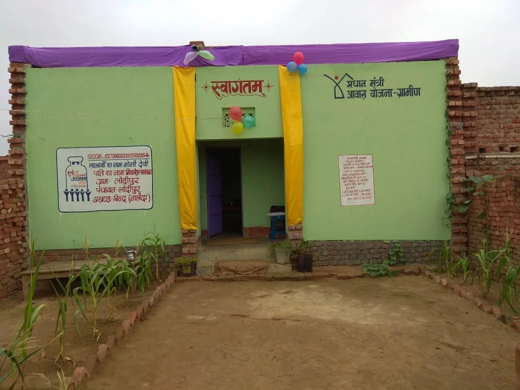 Completed PMAY-G rural house with beneficiary details painted on the wall